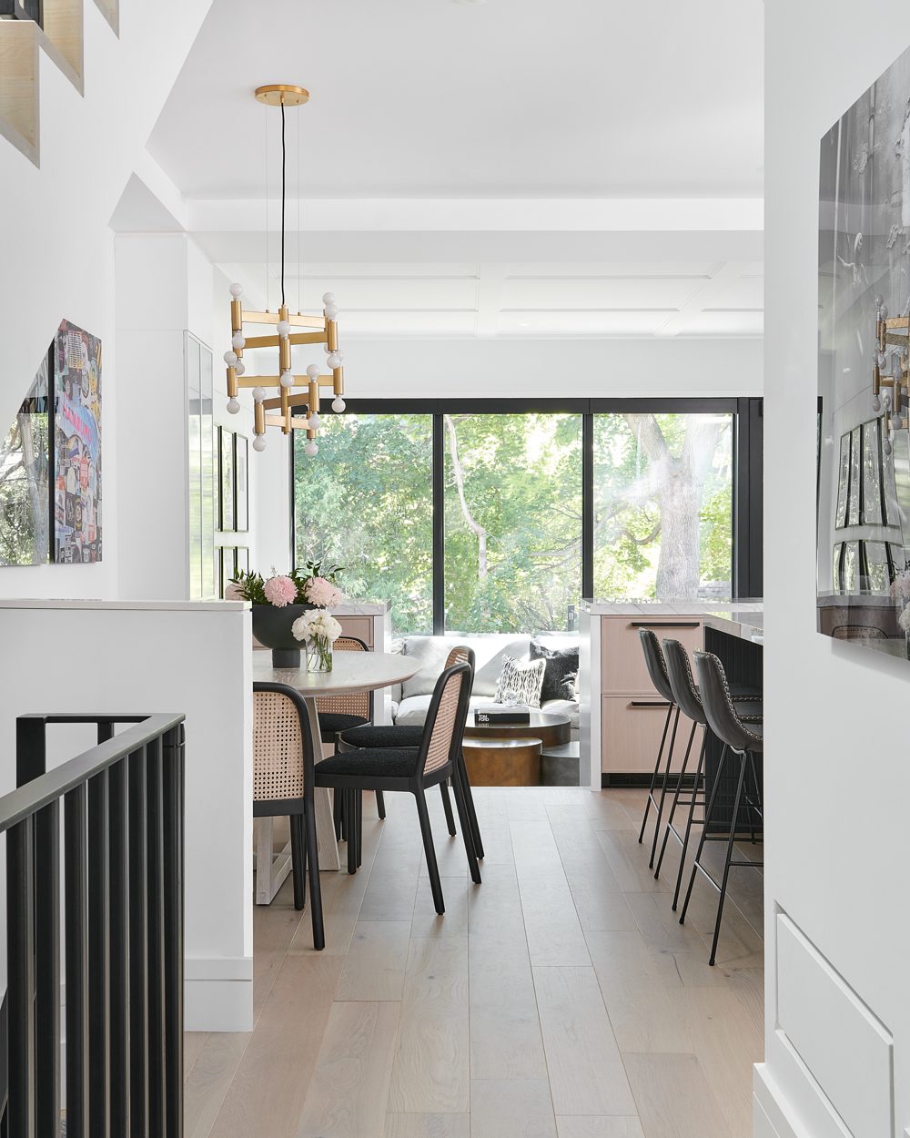 A view through a black steel rail to a dining table under a brass chandelier