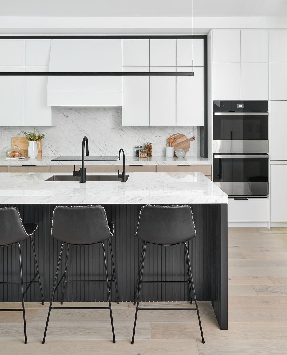 A white kitchen from the island end, with black stools