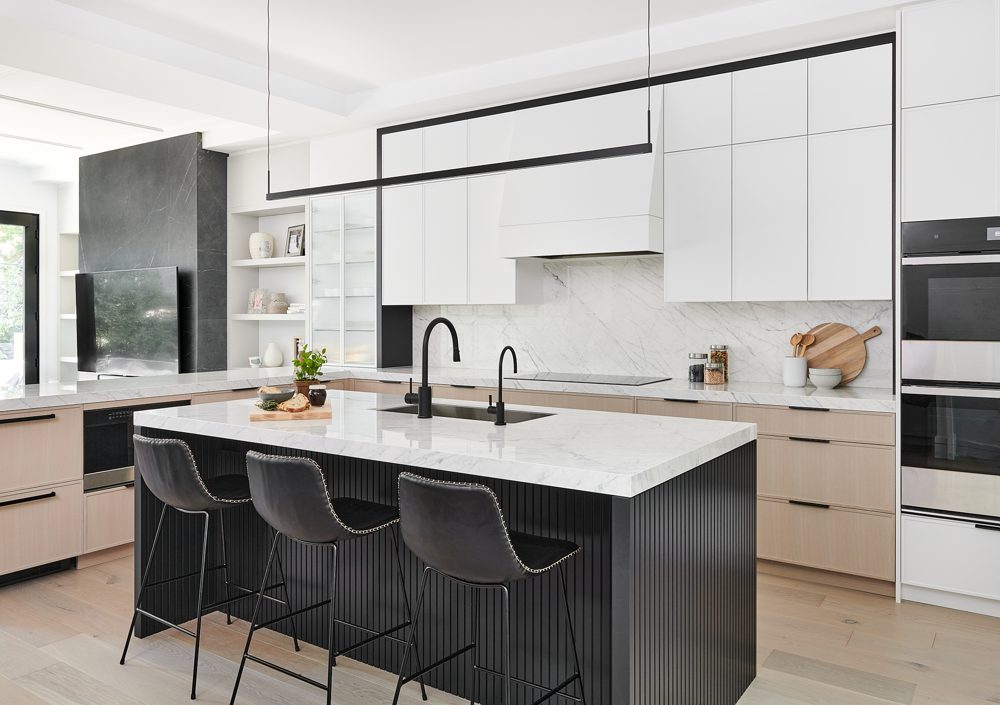 A white kitchen with a black-framed island and a marble backsplash