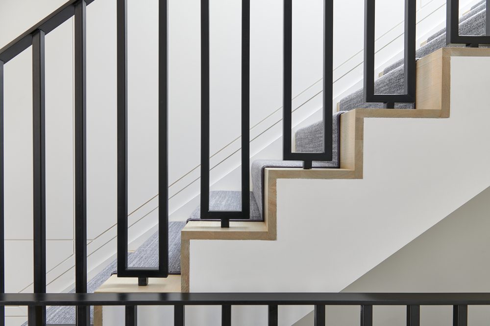 Black steel balusters against white walls, with oak treads and a runner