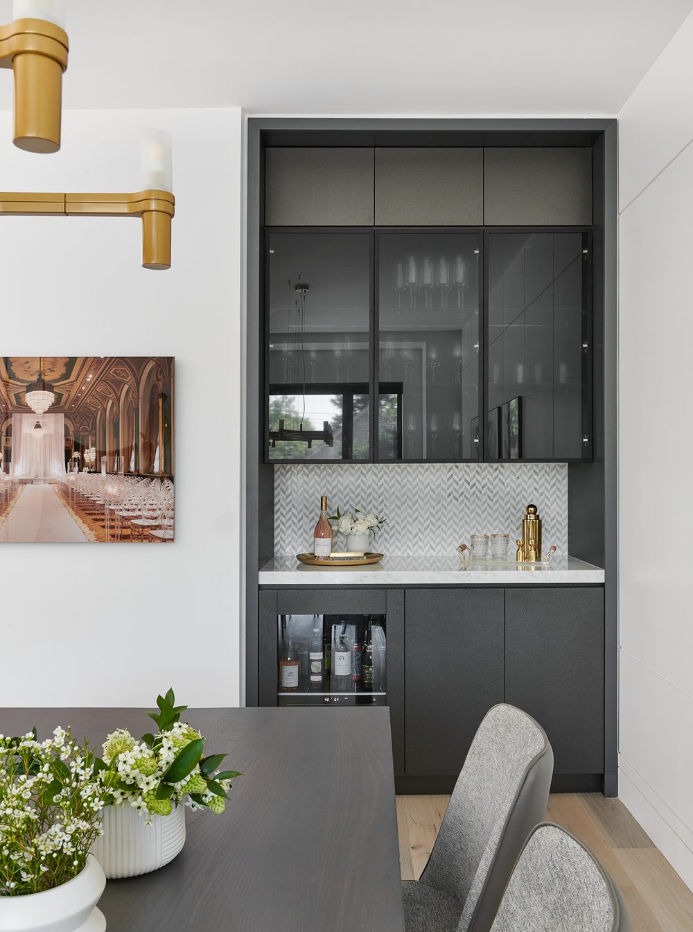 A dark bar cabinet with a lit back and a brass sconce