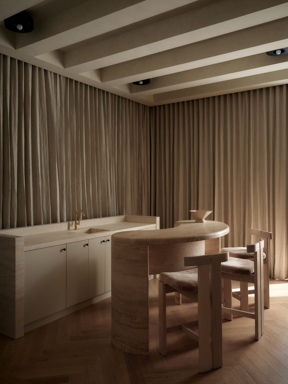 A pale oak dining table under a coffered ceiling, linen curtains on three walls