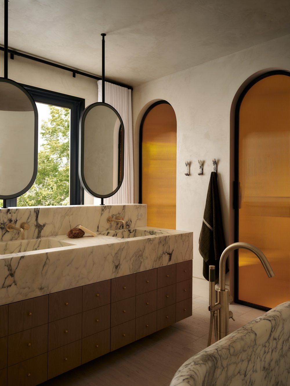 A marble vanity with an amber reeded-glass shower door