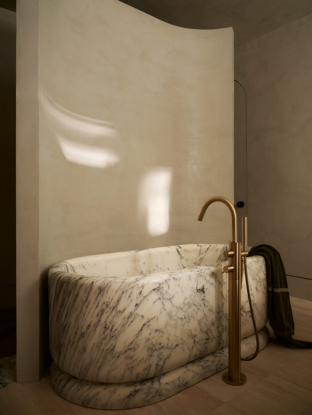 A free-standing marble tub inside a curved plaster alcove