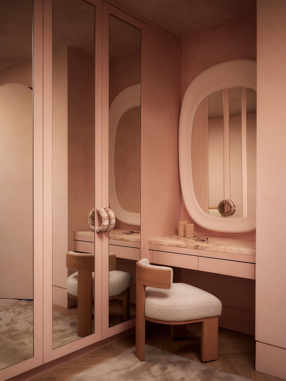 A pink lacquered dressing room with arched mirrors and brass pulls