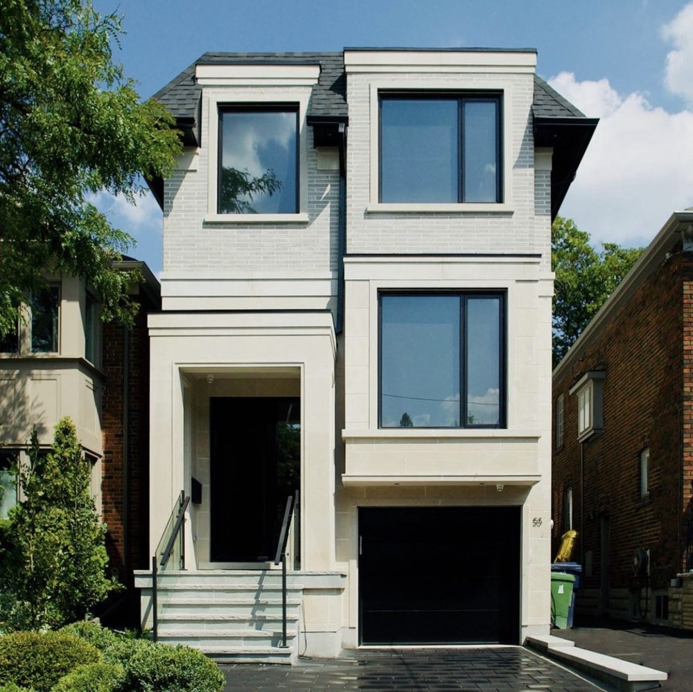 A white-brick three-storey house with black windows and a stepped entry