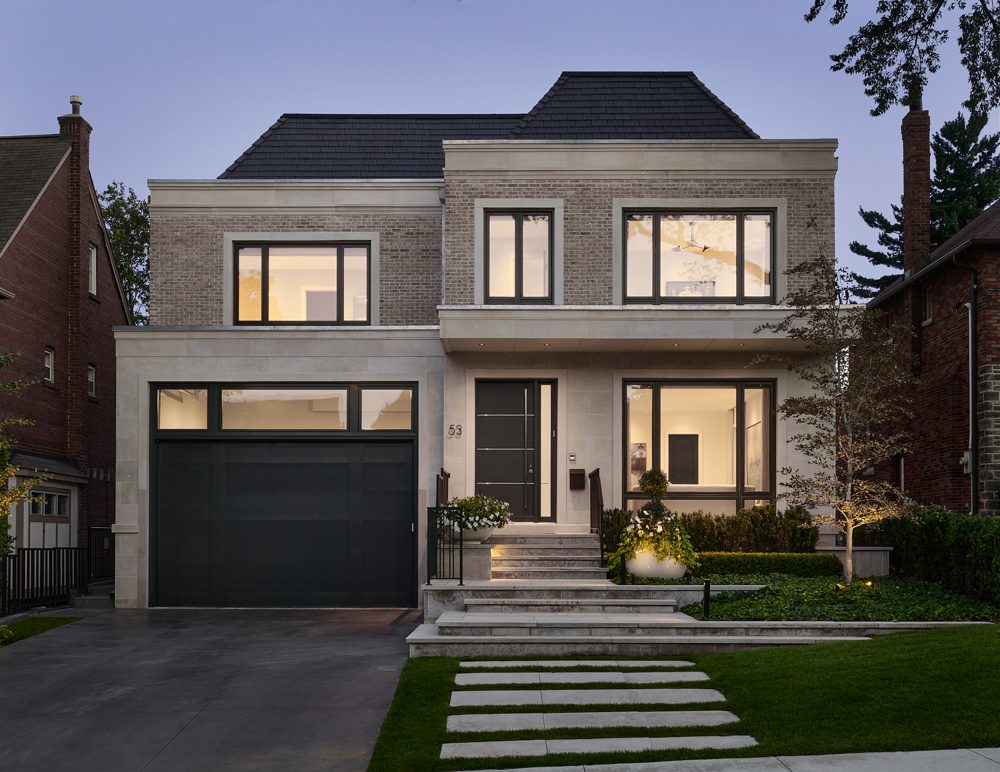 A stone and brick house at dusk with lit windows