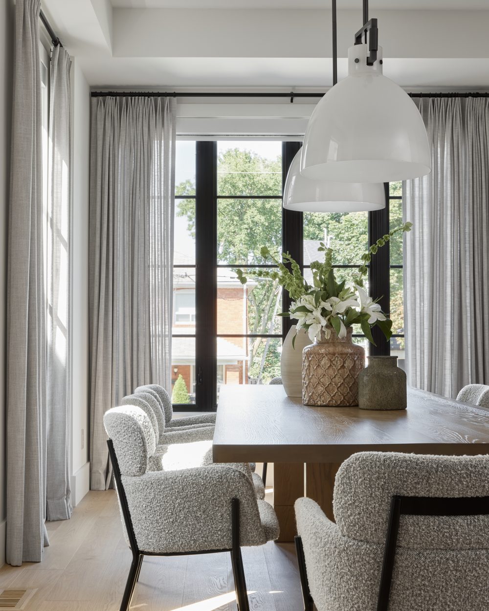 Grey boucle chairs at an oak table under two white dome pendants