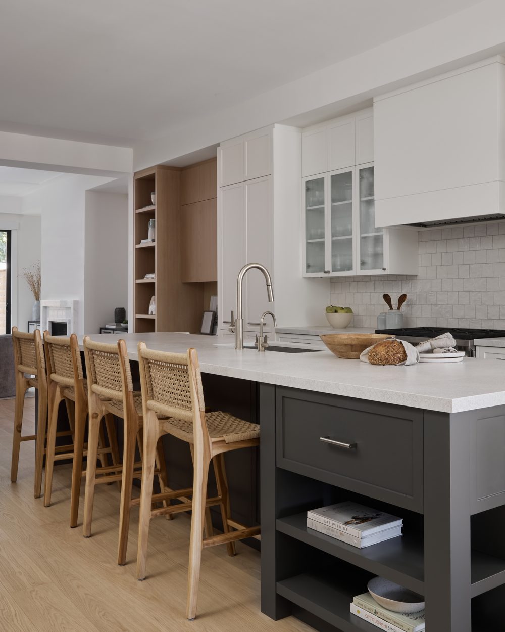 A long charcoal island with a white top, rattan stools and a zellige backsplash