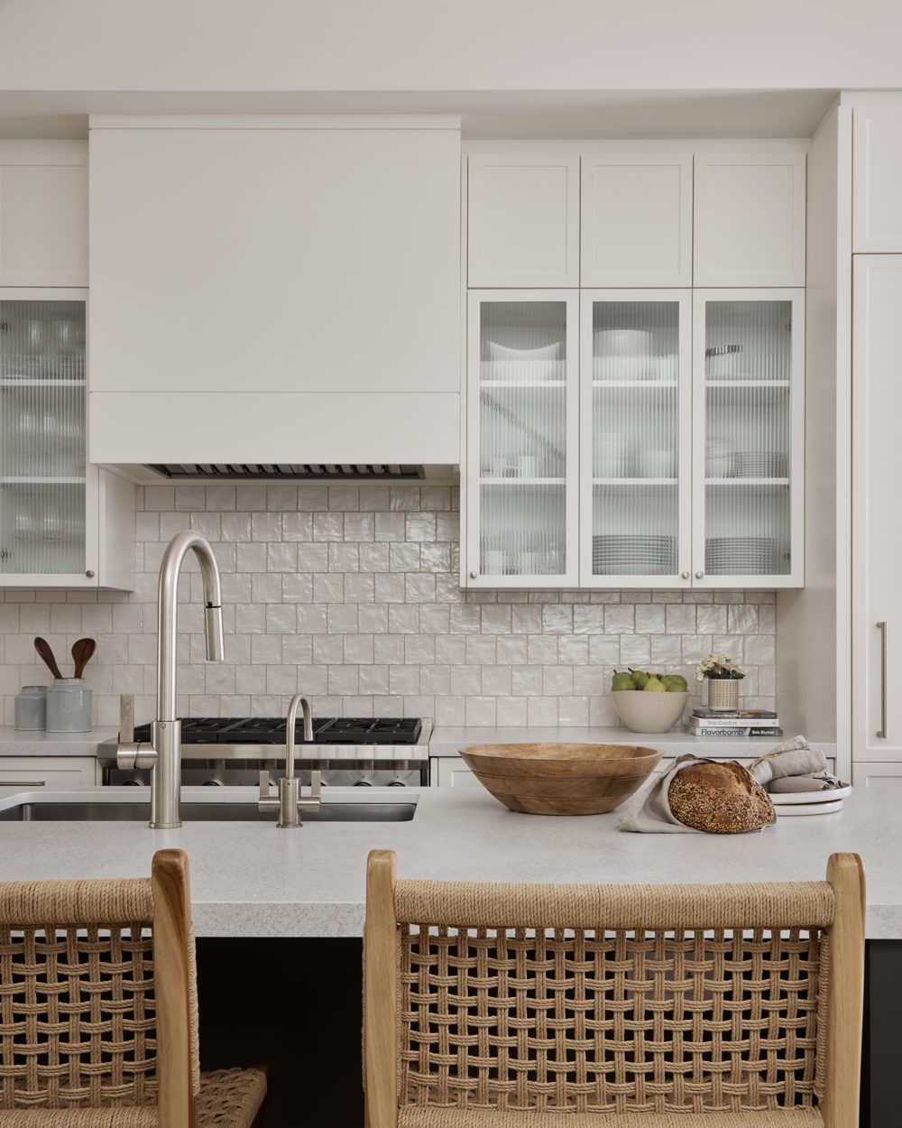 A zellige tile range wall with a white hood and glass-front cabinets