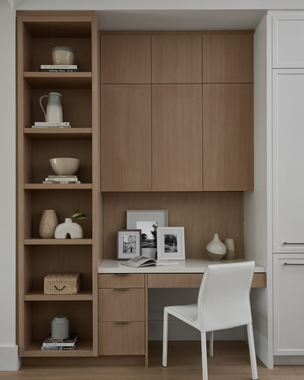 White-oak built-ins with open shelving and a white leather chair