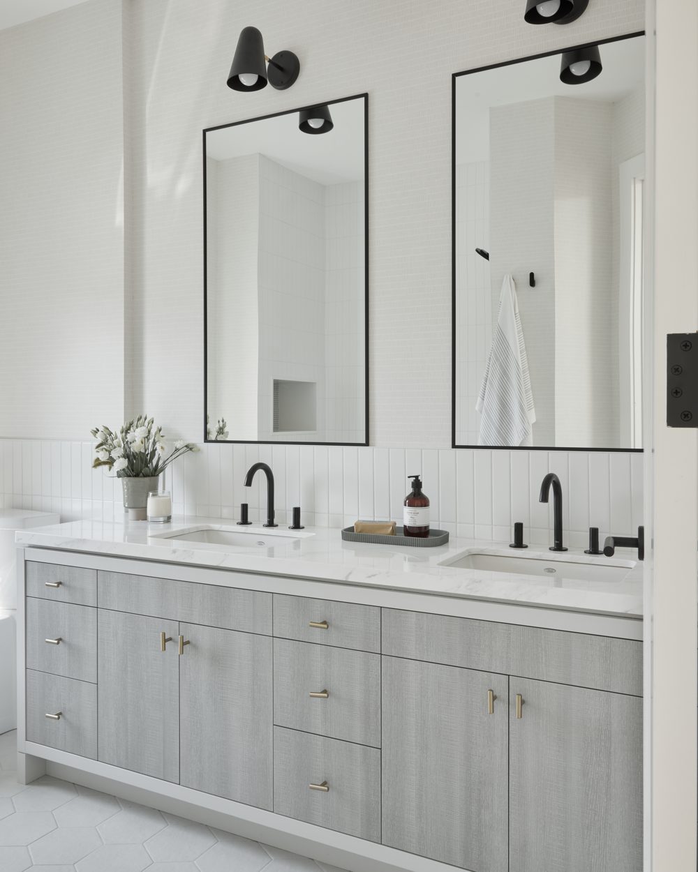 A double vanity in grey oak with black taps and two black mirrors