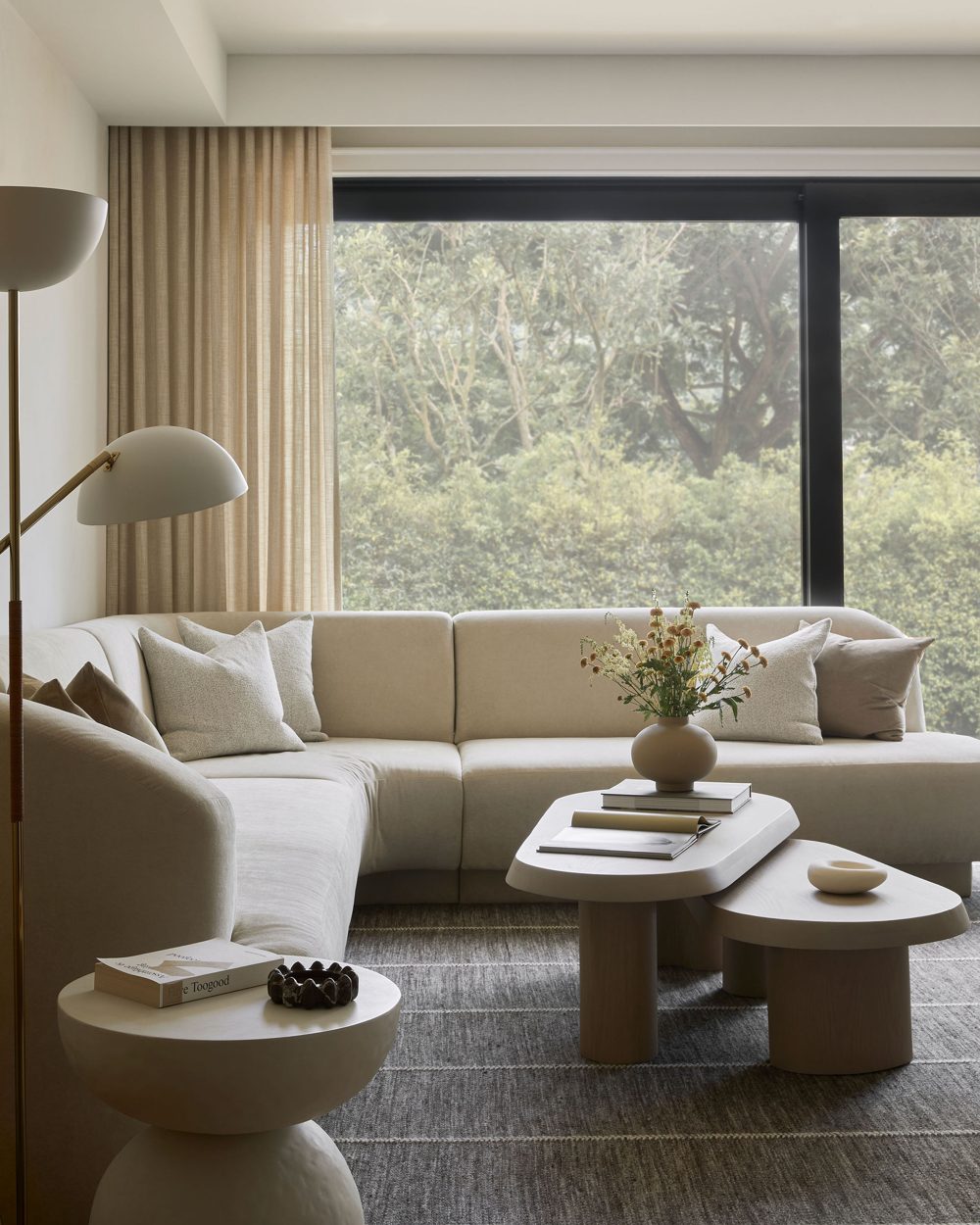 A curved cream sectional in front of a black-framed window