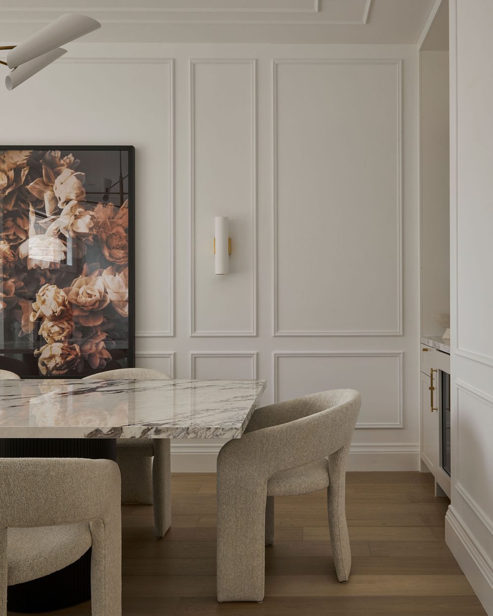 Panel-moulded walls, a floral still life, a marble table and boucle dining chairs