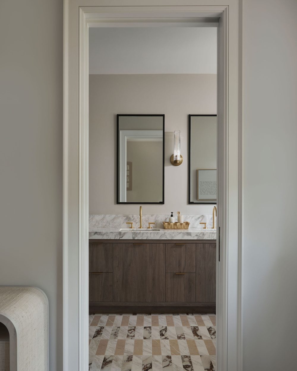 A marble vanity with brass taps seen through a cased opening