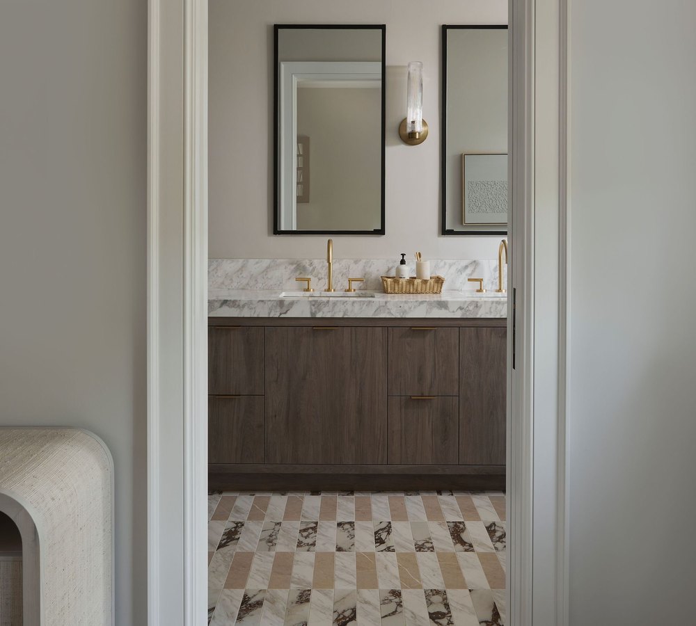 A marble vanity with brass taps seen through a cased opening